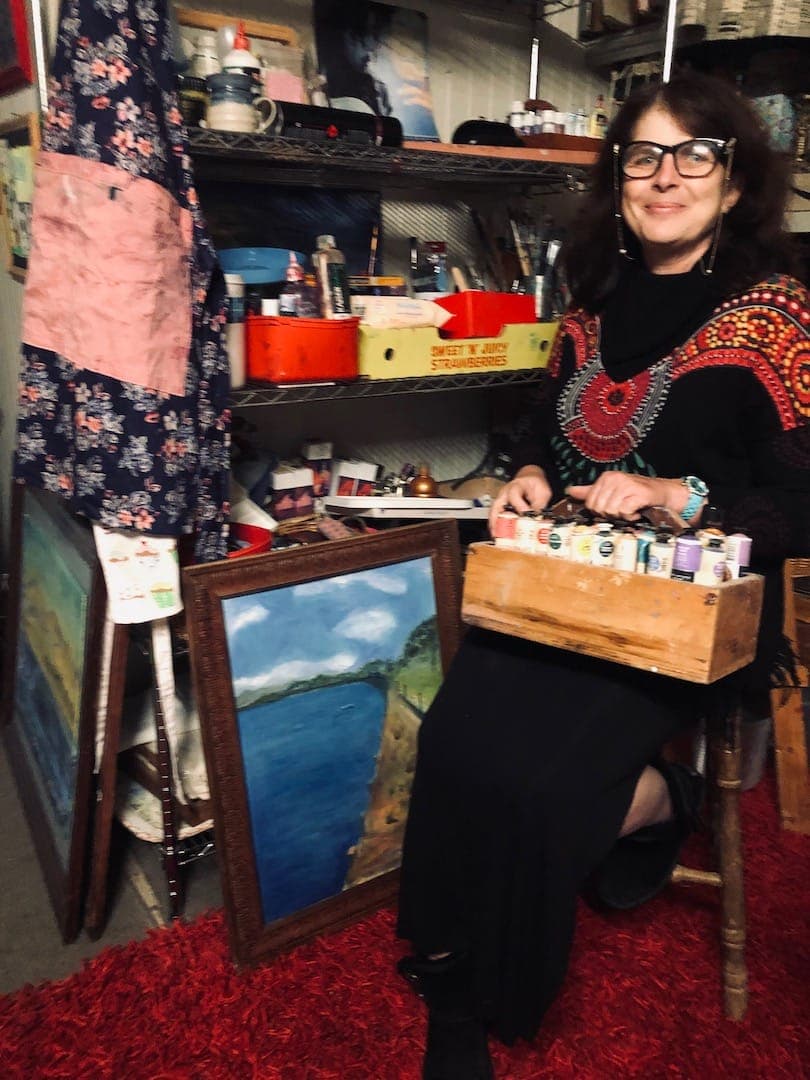 Julie Anne Bartlett in her studio with paintings and art materials